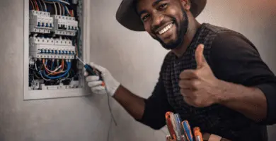 Electricista a domicilio revisando tablero eléctrico con cinturón de herramientas; atención el mismo día.